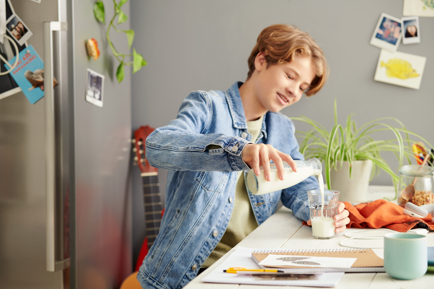 Lifestyle fotografie tiener schenkt glas melk in